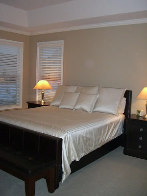 A shiny off white bedding on a dark wooden bed frame.