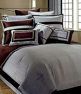 Dark red and soft gray bedding a lots of pillows.
