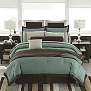 White, teal and dark brown comforter on a bed.
