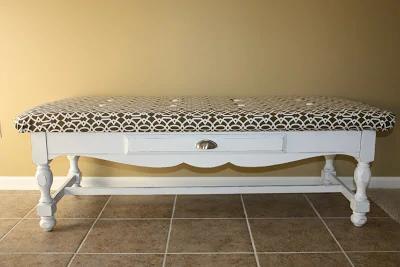 The white table with a brown and white cushion on the top.