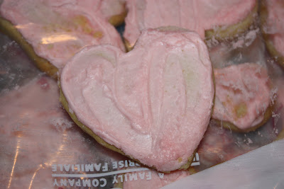 A heart shaped cookie with pink icing.