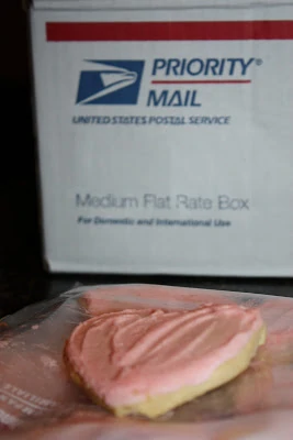 A heart shaped Valentines love cookie with a priority mail package.
