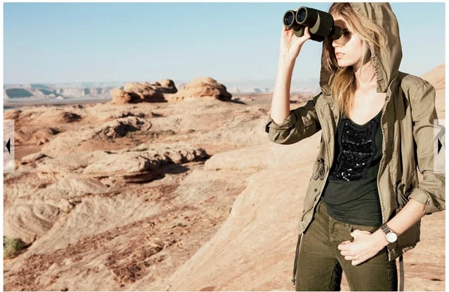 The model looking into binoculars over the desert.