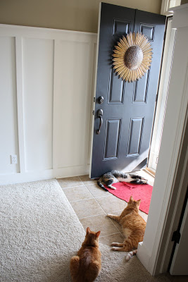 The front door is ajar showing the sunflower wreath hanging on it.