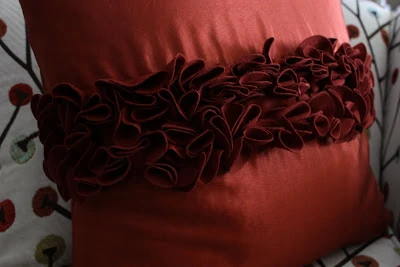 A dark red ruffled pillow on the couch.