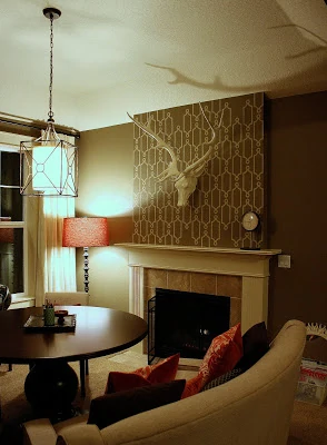 A living room with a fireplace, a wall feature above the fireplace with antlers on a stencilled wall.
