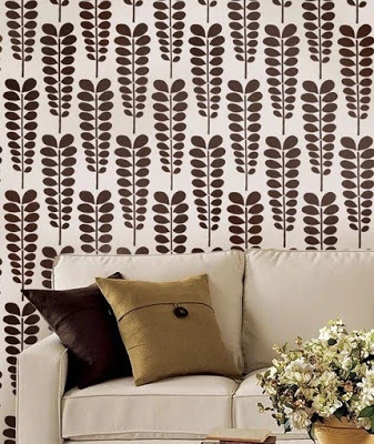 A brown stencil that looks like leaves above a neutral couch.