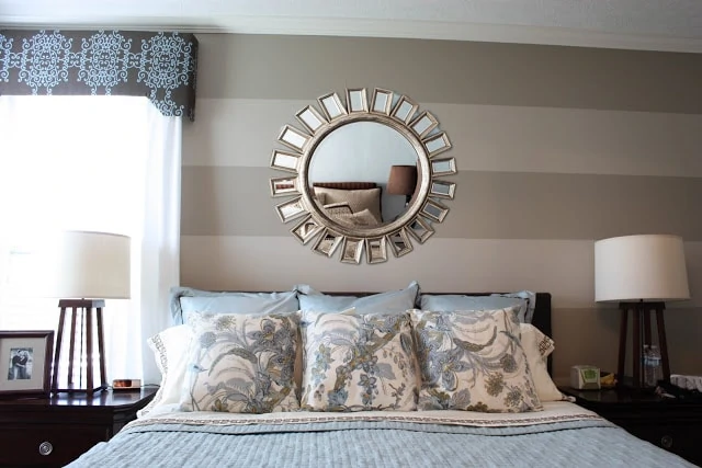 A large gold sunburst mirror is on the wall above the headboard.