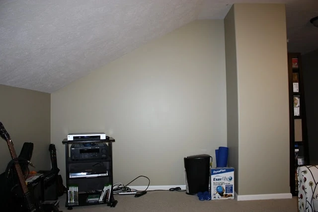 A small room with a sloped ceiling and musical items in the room.
