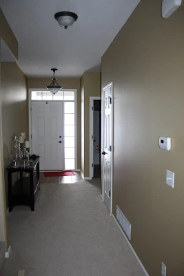 Long hallway painted off white with a white door at the end.