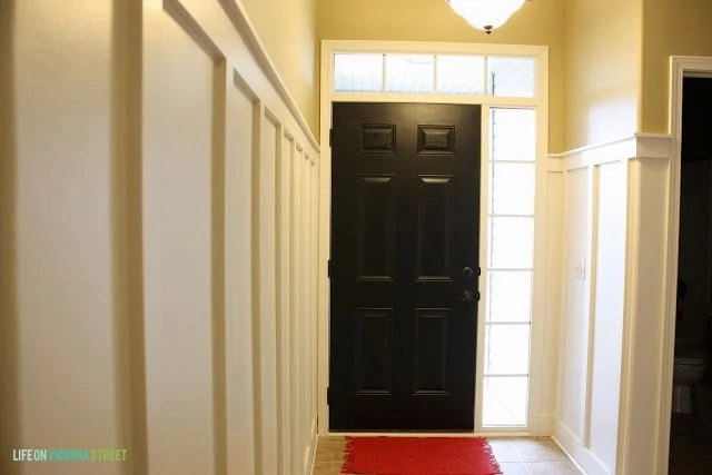 The door painted black with the light on in front of it.