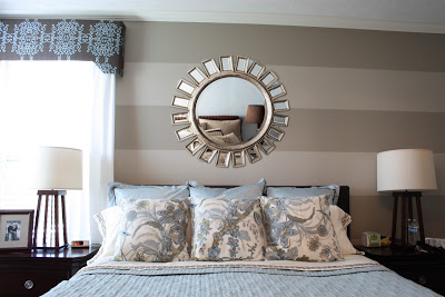 A round mirror above the bed in the master bedroom.