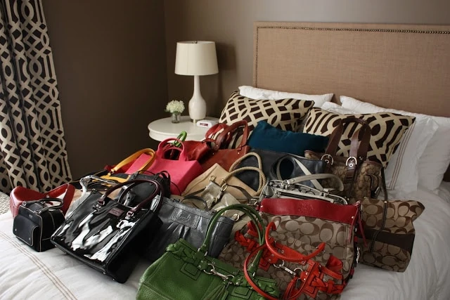 Many purses all laid out on the bed taking up the whole bed.