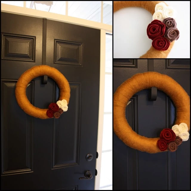 Yarn and felt flower wreath hanging on dark wood door.