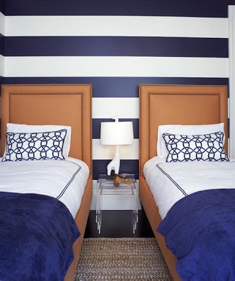 Striped blue and white walls with two single beds in front of it.