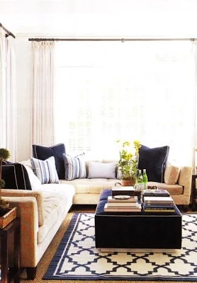 A sectional couch in the living room with a blue and white rug.