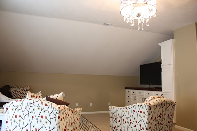 Fabric armchairs, and a chandelier are in the bonus room.