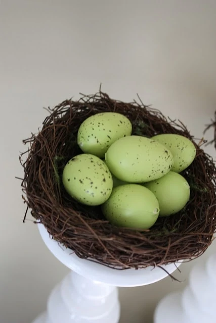 A twig bird nest with faux green bird eggs in it.