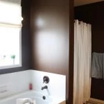 White bathtub and brown walls in bathroom.