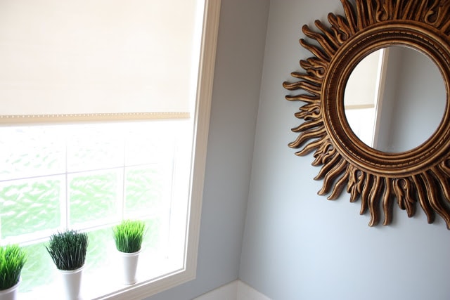 Little pots of greenery by the window in the bathroom and the large gold mirror above the tub.