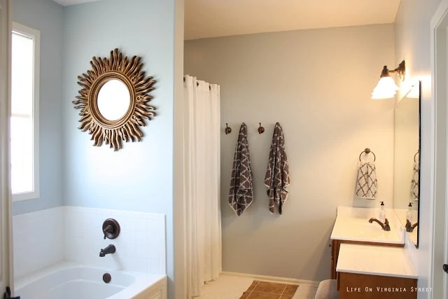 Master Bathroom painted Light French Gray by Behr and towel hooks with brown and white towels on them.