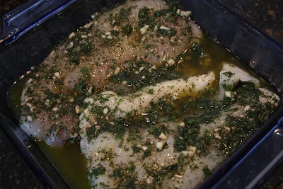 Fish in a pan with the green and garlic marinade on top.