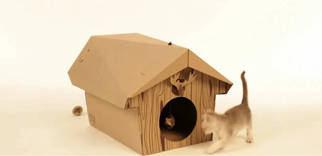 A cardboard/wood little cabin for a cat with a tiny moose head above the opening.