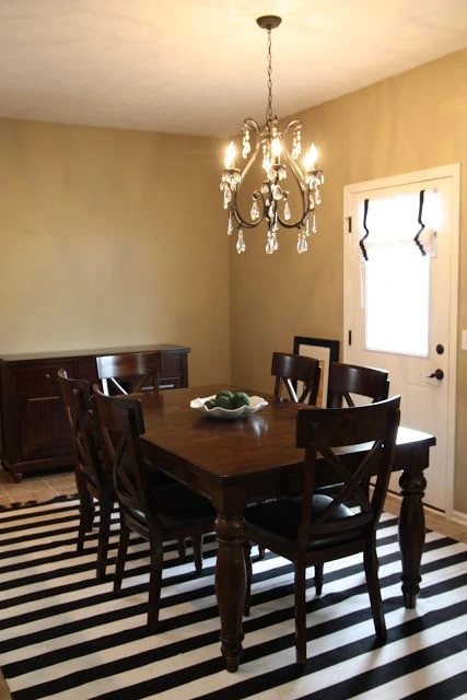 Dining room with striped rug, a chandelier, and a dark wood dining room table set.