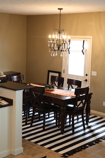 Crystal chandelier, striped run, and table in room.