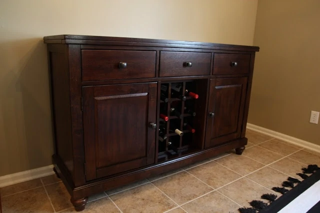 Wooden dining room hutch with a spot for wine bottles.