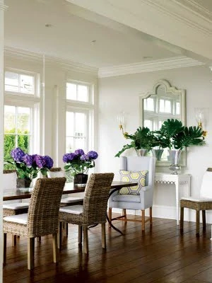 Wooden floors, dining room table with purple flowers on it.