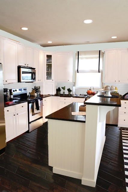 A mostly white kitchen with dark counters and floors.