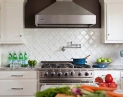 White tile with a pot filler and a stove in front of it.