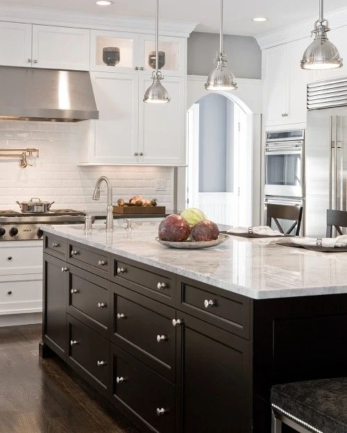 White subway tile in kitchen with a dark brown island and a white marble top.