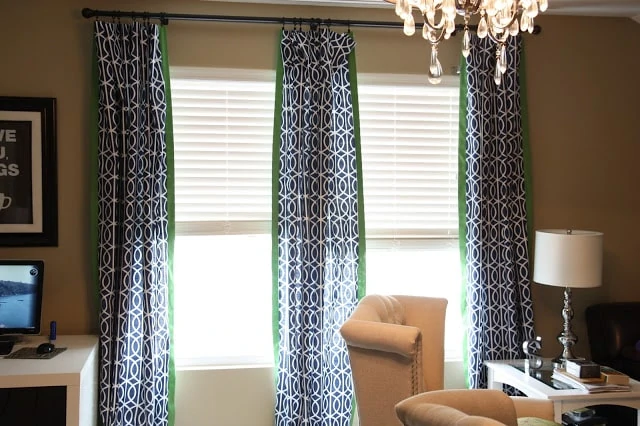 A bonus room with a small table, chandelier and patterned curtains hanging in the room.