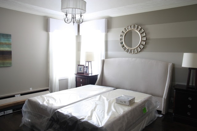 Setting up a bed in the bedroom with a mirror on the striped wall.
