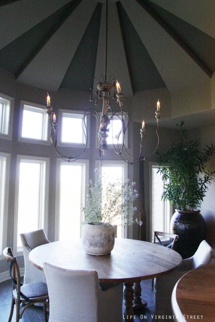 A round kitchen table with a simple chandelier hanging above it.