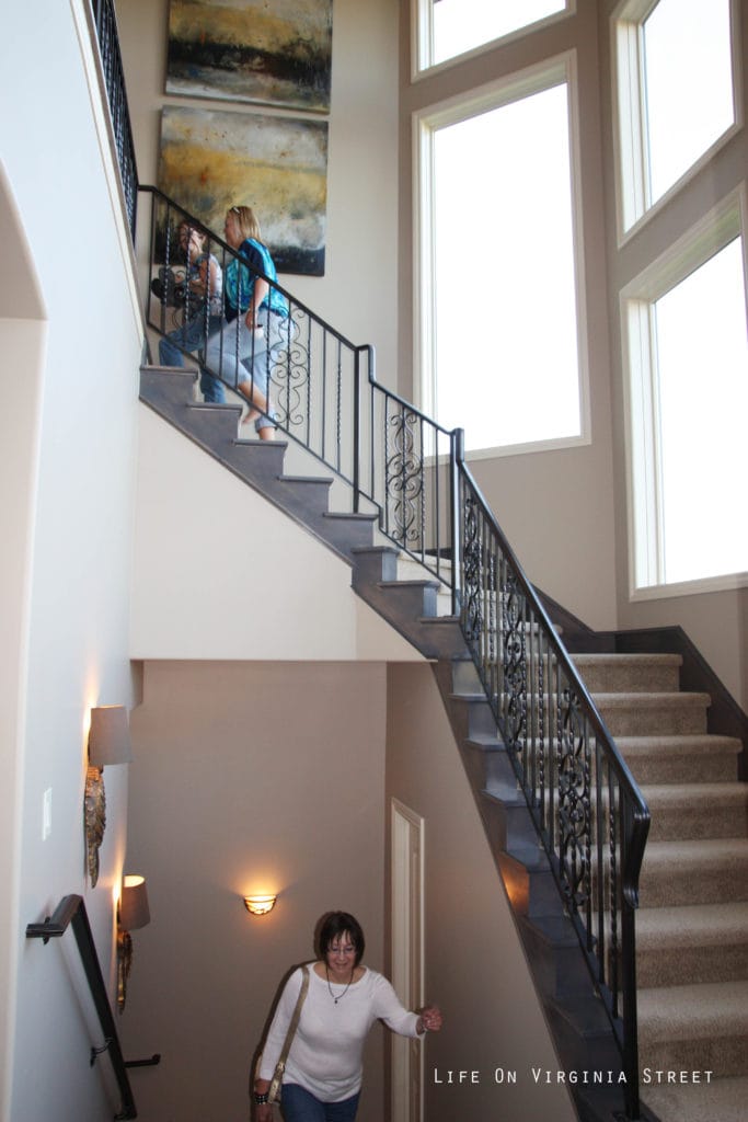 Woman walking up the long staircase with wrought iron.