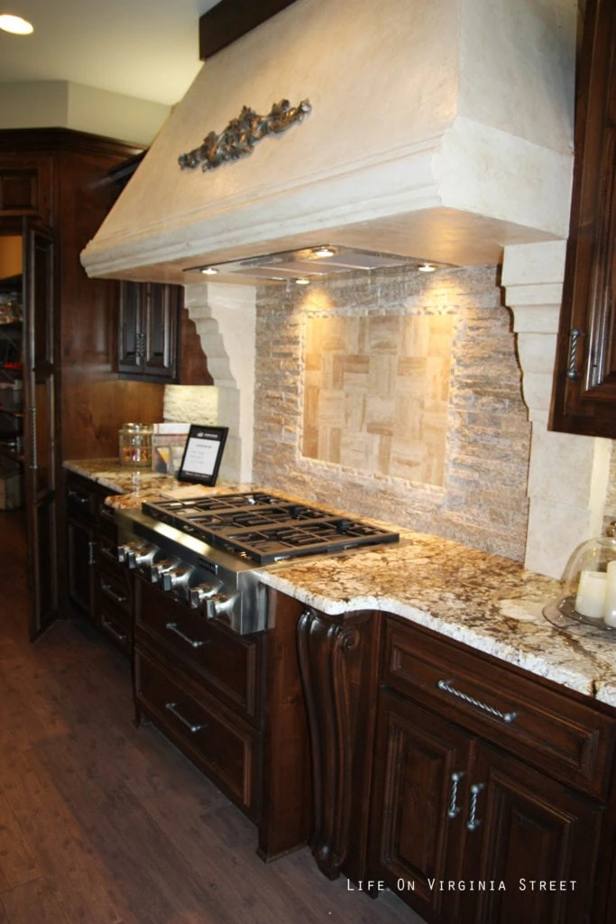 A large ornate kitchen hood above the stove with wooden cabinets.