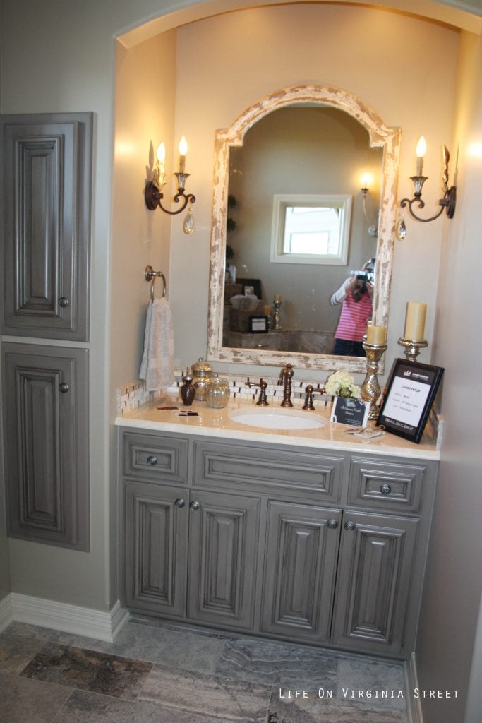 French-style master bathroom with gray painted vanity and candle sconces.