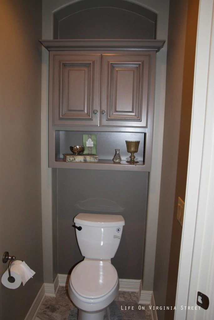 A cabinet built around the toilet in the bathroom.
