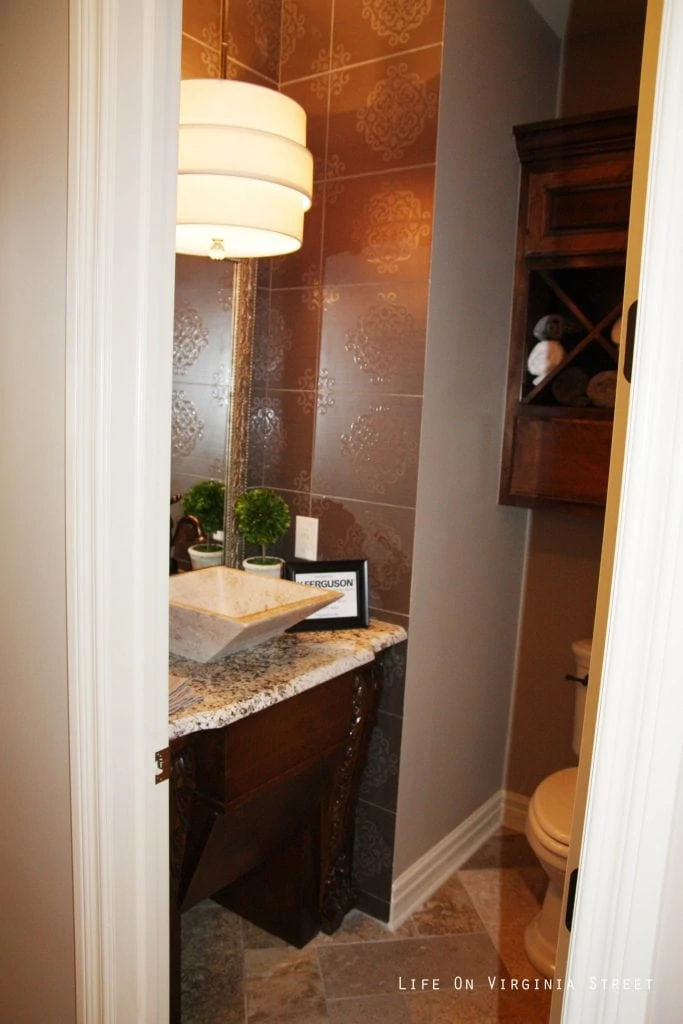 A small power room with a wood cabinet and marble tops.
