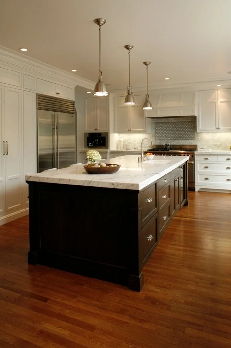 Wooden floor and dark wood and white island in kitchen.