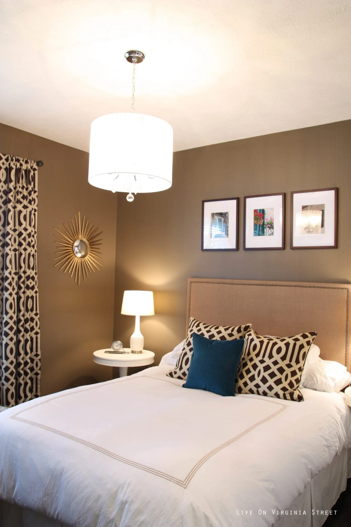 A medium brown guest bedroom with white bedding a brown and turquoise pillows on the bed.