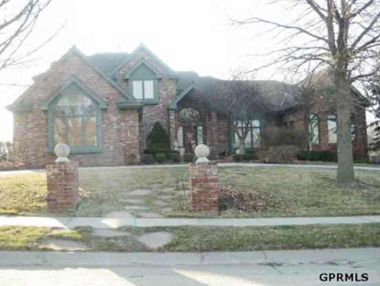 A large brick house with a soft green trim around the windows.
