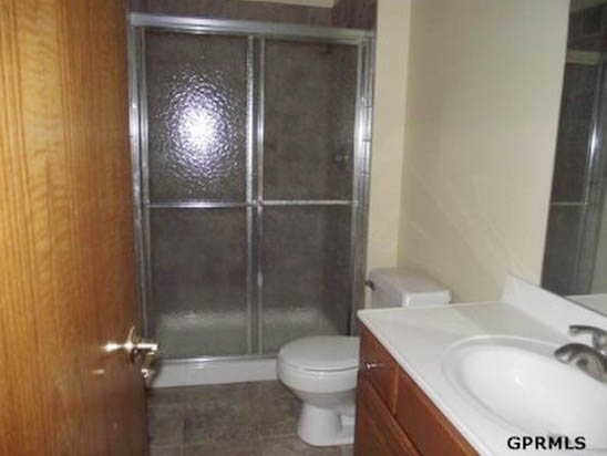 A small bathroom with a shower stall and a white sink.