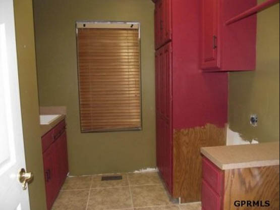 A laundry room with painted red cabinets and olive color on the wall.