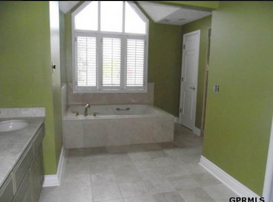 A fresh bright green in the bathroom with a tub in the corner.