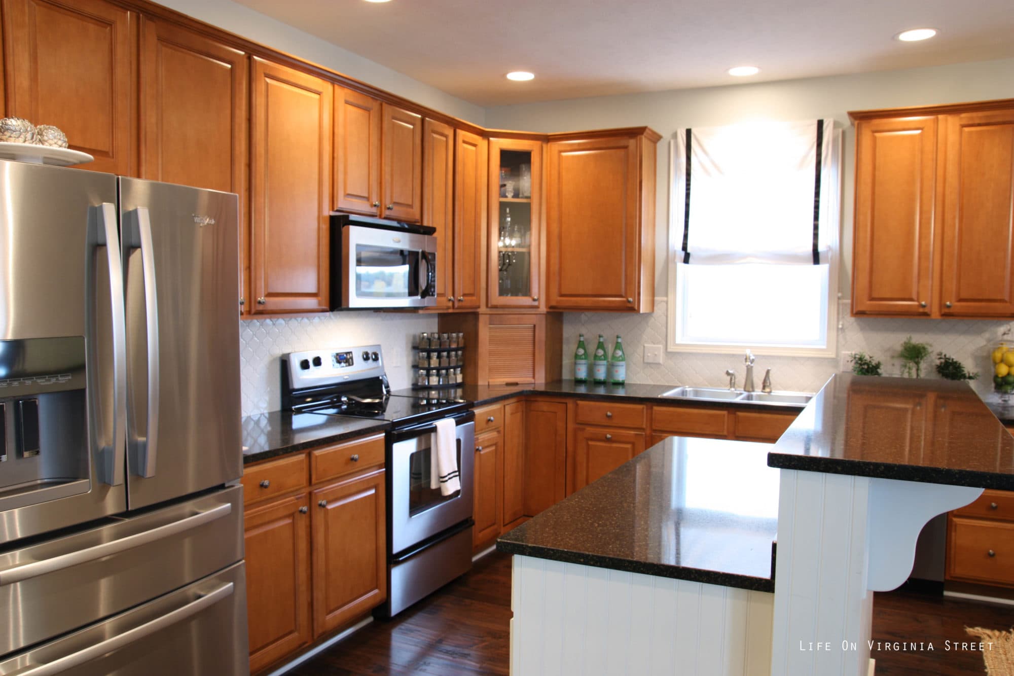 A large kitchen with wood cabinets and a black and white island.
