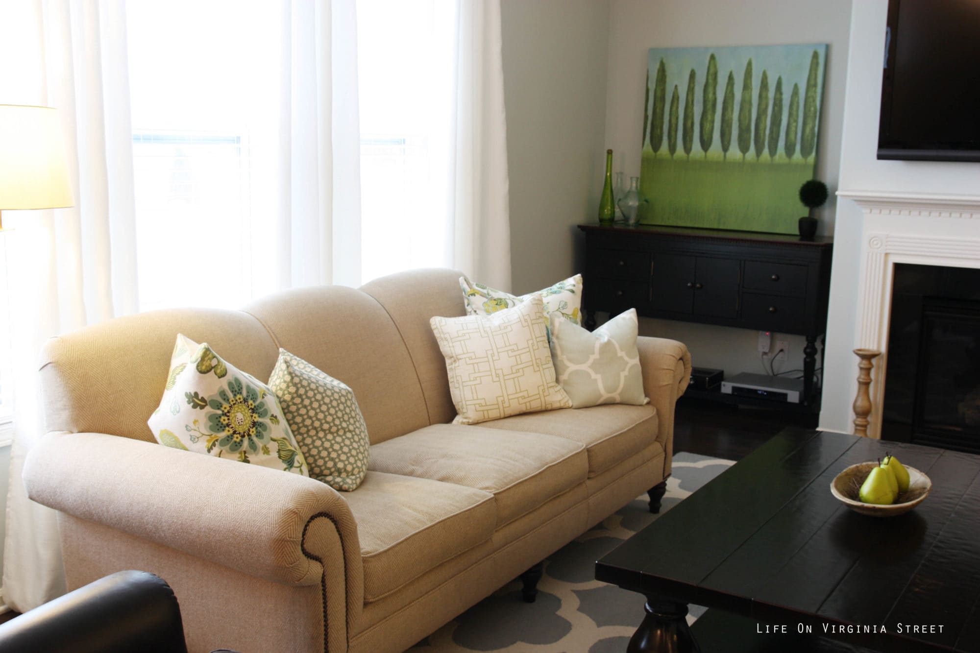 There is a large green woodsy picture beside the fireplace in the living room.